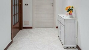 A hallway with a closed door, a white cabinet with a vase of flowers, and a wall-mounted mirror. - Augusto 42 apartment Napoli.  Stadium Metro & Free Parking (Napoli)