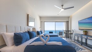 Camera d'albergo con un letto grande, una scrivania, una sedia, una televisione e vista sull'oceano.