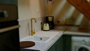 Une cuisine compacte équipée d’un évier, d’une machine à café et d’un lave-linge.