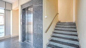 A modern interior with a marble elevator and a staircase with metal railings. - Classic Royal Rooms (Bengaluru)