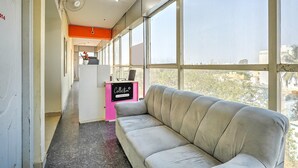 A modern office interior with a grey sofa, large windows, and a reception desk. - Classic Royal Rooms (Bengaluru)