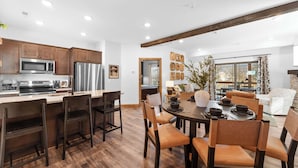 A modern kitchen with wooden cabinets, stainless steel appliances, and a dining area with a round table and chairs.