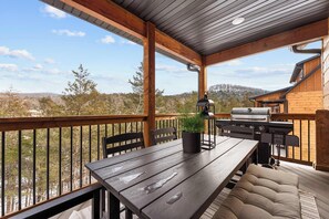 Eine Holzterrasse mit Tisch, Stühlen, einem Grill und einem Blumentopf.