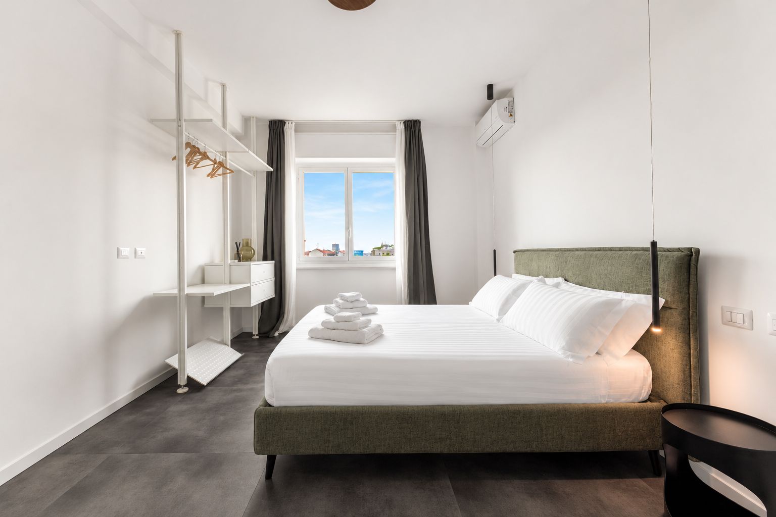 Een moderne hotelkamer met een bed, een bureau en uitzicht op de stad.