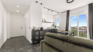 Een modern appartement met woonkamer, kitchenette en balkon met uitzicht over de stad.