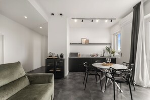 A modern kitchen with a dining area, a sofa, and a view of the outdoors. - Modern and cozy penthouse for independent living with all amenities. (Milano)