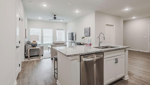 Una cocina moderna con una isla grande, electrodomésticos de acero inoxidable y una zona de comedor con sofá y mesa.