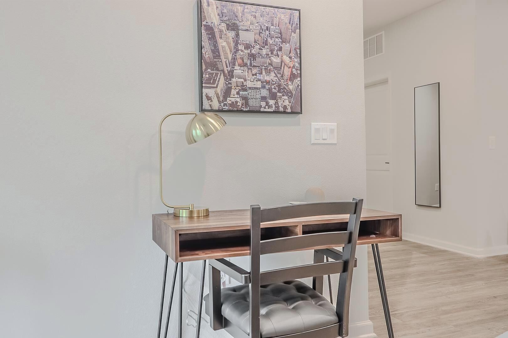 Et moderne arbejdsområde med et skrivebord, stol og et bybillede på væggen.
