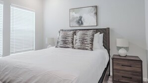 Un dormitorio con una cama, dos lámparas de noche, una mesita de noche y un cuadro en la pared.