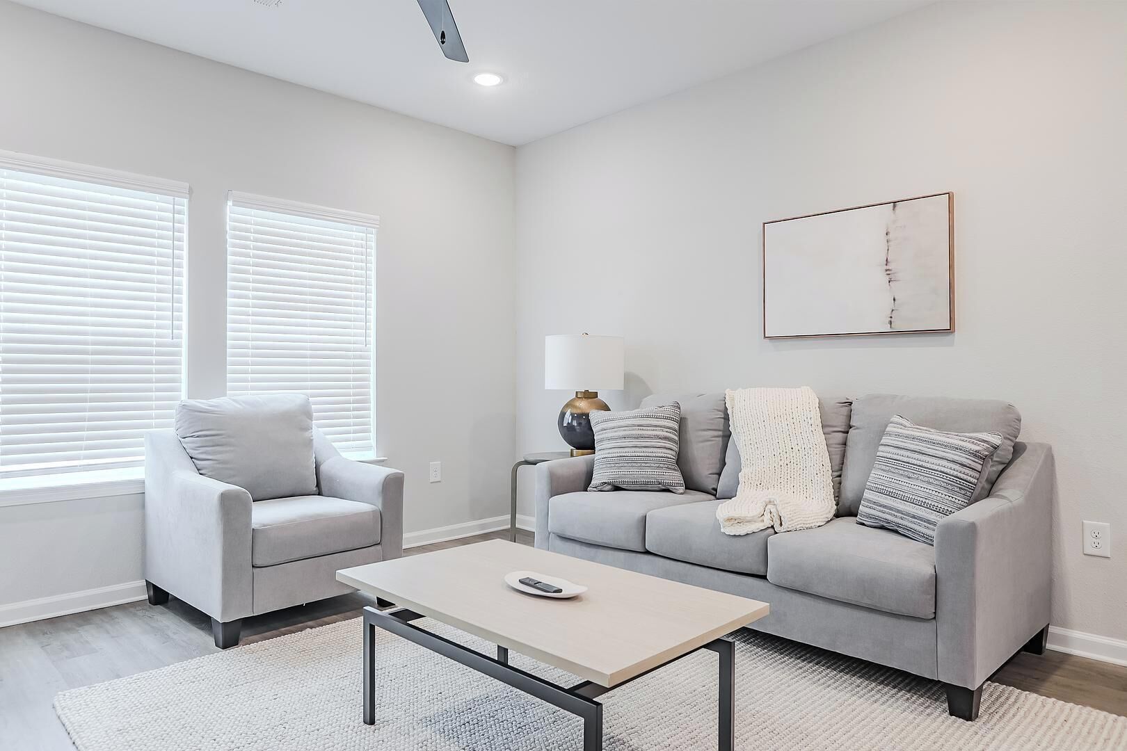 A modern living room with a grey sofa, a matching armchair, and a coffee table.