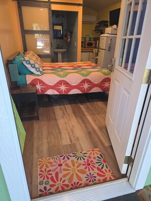 A bedroom with a bed, a nightstand, a dresser, a window, and a door.