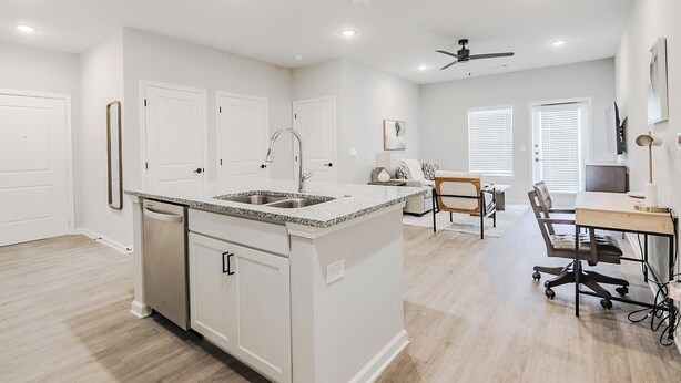 A modern kitchen with a central island, white cabinetry, and a dining area with a table and chairs. - Landing | Chic 1BD, Gym, Clubhouse (San Marcos)