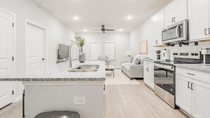 Une cuisine moderne avec des meubles blancs, des appareils en acier inoxydable et un plan de travail en granit.