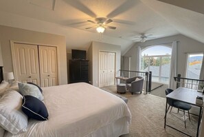 A bedroom with a bed, a desk, and a balcony with a view. -     Sylvan Lake Family Retreat | 5-Min Walk to Beach | Sleeps 10 (Sylvan Lake)