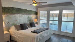 A bedroom with a large bed, a ceiling fan, and a view of a lake through the windows. -  3Bed2Bath Waterfront Condo - Alluring Main Channel and Pool Views! (Osage Beach)