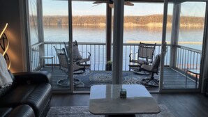 A modern living room with a large sliding glass door leading to a balcony overlooking a lake. -  3Bed2Bath Waterfront Condo - Alluring Main Channel and Pool Views! (Osage Beach)
