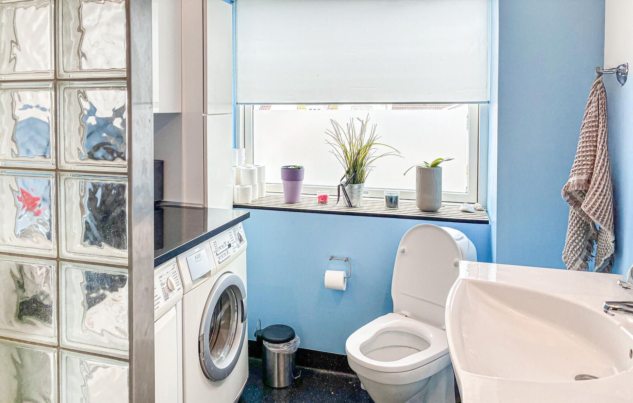A compact bathroom with a washing machine, toilet, and sink.