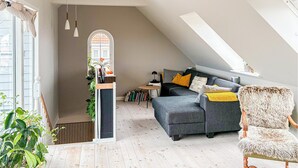 A loft-style living room with a grey sofa, a furry chair, and a staircase leading to an upper level. - 3 bedroom lovely apartment in Korsør (Korsør)