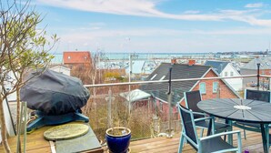 A deck with a table and chairs, overlooking a marina with boats and buildings. - 3 bedroom lovely apartment in Korsør (Korsør)