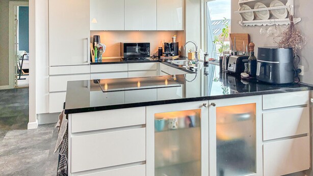 A modern kitchen with white cabinetry, a black countertop, and stainless steel appliances. - 3 bedroom lovely apartment in Korsør (Korsør)