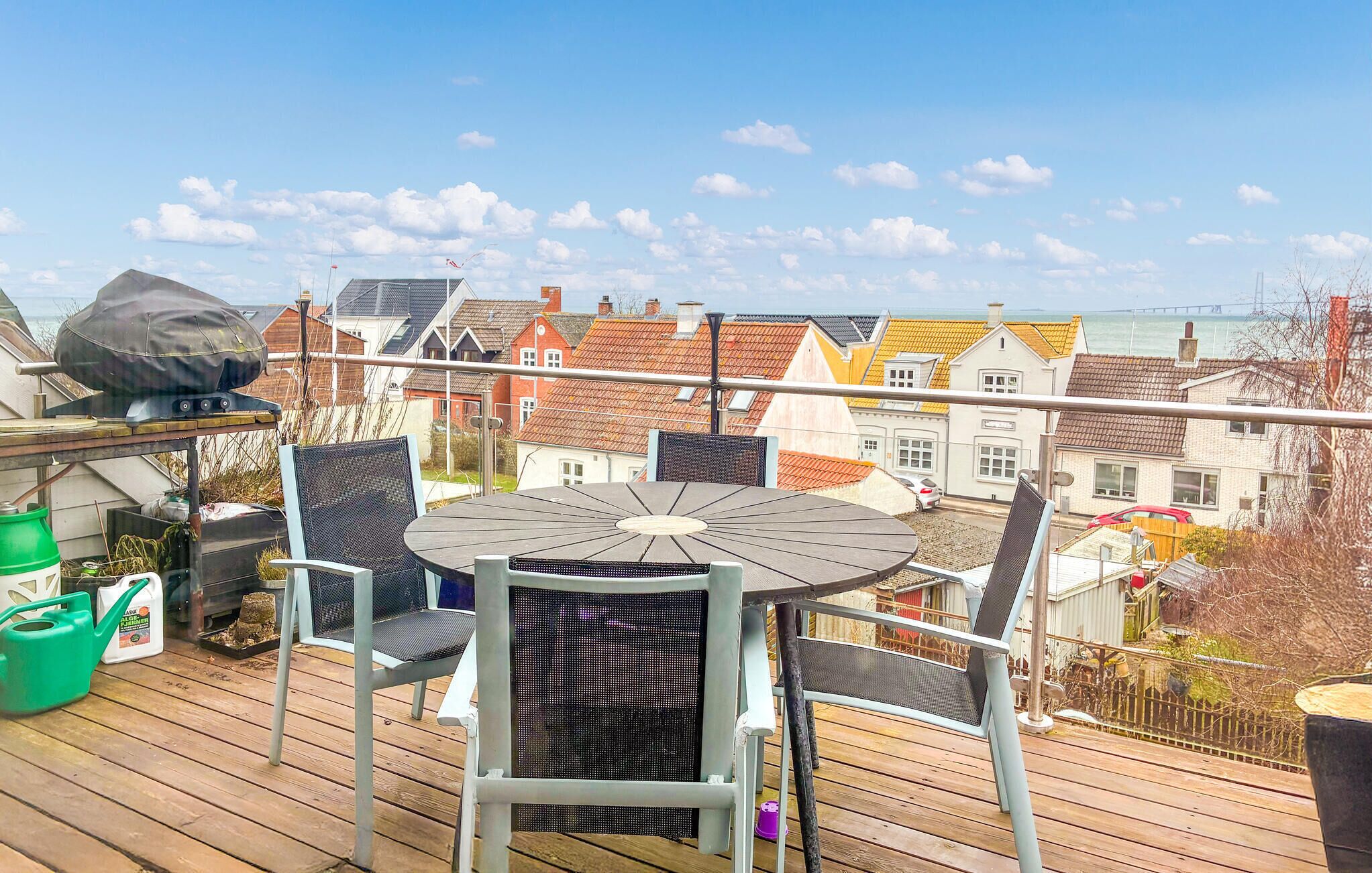 Un balcon avec une table ronde et des chaises, donnant sur un quartier résidentiel aux maisons aux couleurs vives.