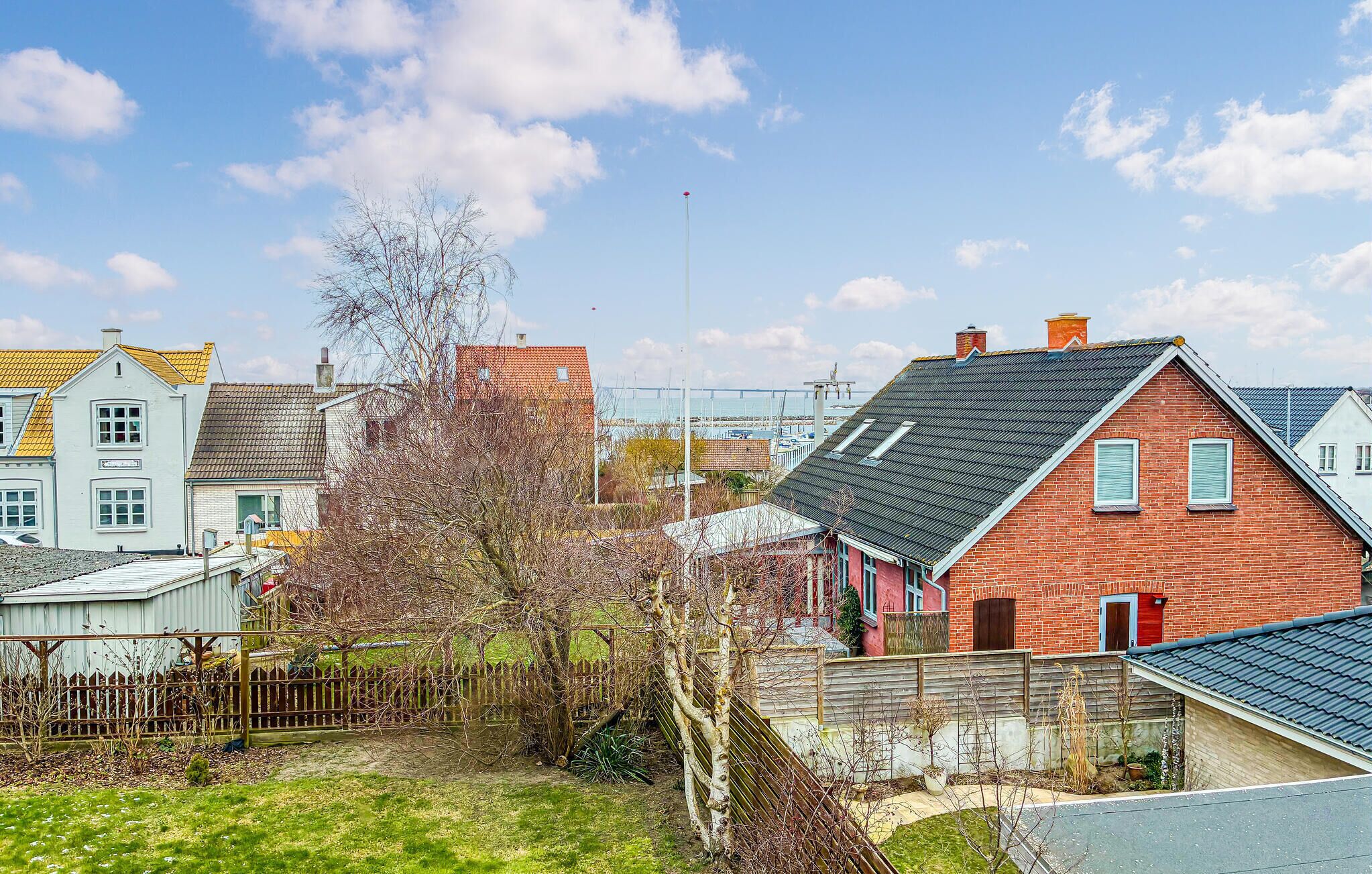 Un barrio residencial con varias casas, incluyendo una de ladrillo rojo con techo inclinado y otra blanca con techo a dos aguas.