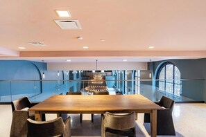 Une salle de conférence avec une longue table, des chaises, un lustre et une grande fenêtre.