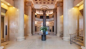 A grand lobby with marble columns, a central fountain, and a staircase. - Landing | Stunning 1BD in Downtown Hartford (Hartford)
