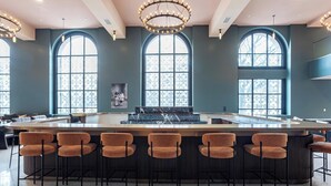 A bar area with a marble countertop, six bar stools, and large arched windows. - Landing | Stunning 1BD in Downtown Hartford (Hartford)