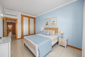 Ein Hotelzimmer mit Bett, Nachttischen, einem Kleiderschrank und einer Klimaanlage.