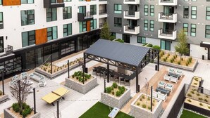 Un moderno complejo de apartamentos con varios balcones, zonas de estar exteriores y un patio cubierto.