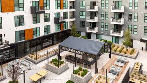 Een modern meerlaags gebouw met buiten zitplaatsen, plantenbakken en een overdekt terras.