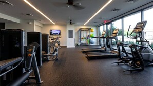 Een moderne sportschool met loopbanden, krachtermaten en een televisiescherm.