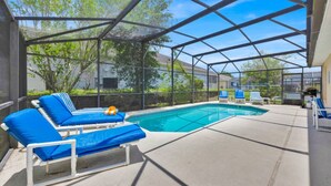 Une piscine extérieure couverte, dotée de chaises longues bleues et d’un espace barbecue.