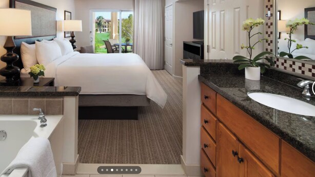 A hotel room with a large bed, a bathroom with a bathtub and sink, and a view of the outdoors. - Relaxing Marriott Shadow Ridge 2-bedroom resort in peaceful Palm Desert (Palm Desert)