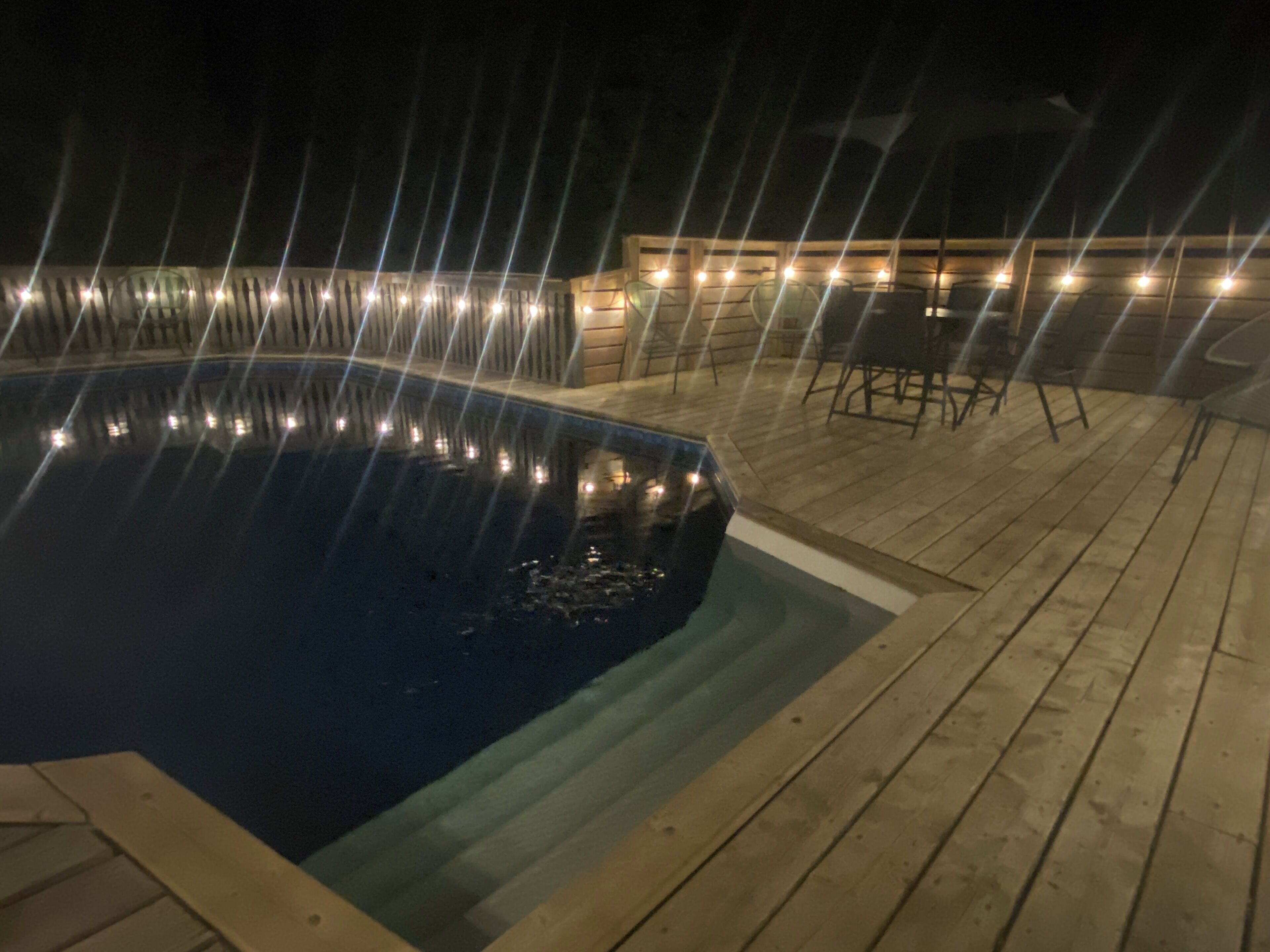 Une piscine dotée d’une terrasse en bois et d’un espace salon extérieur.