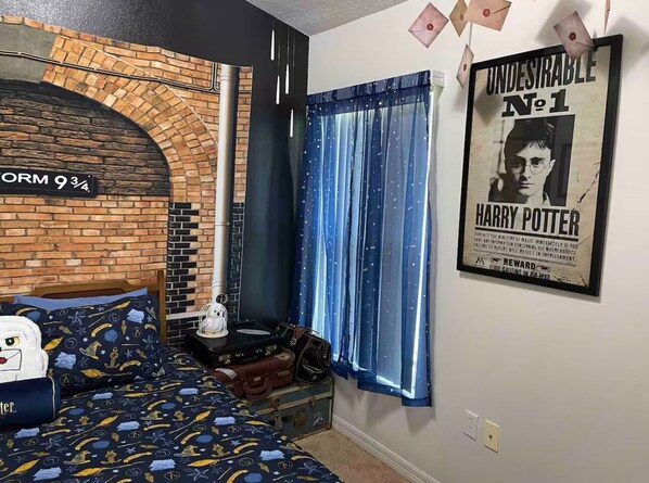 Une chambre avec un mur en briques, un lit recouvert d’une couette aux motifs de Harry Potter, une affiche de Harry Potter, numéro 1, et une fenêtre avec des rideaux bleus.