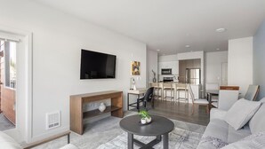 Una sala de estar moderna con un televisor de pantalla plana, una chimenea y un comedor con una cocina al fondo.