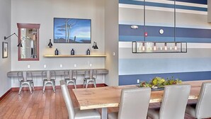 Una sala de reuniones moderna con una mesa de madera, sillas grises, un cuadro grande y una pared azul a rayas.