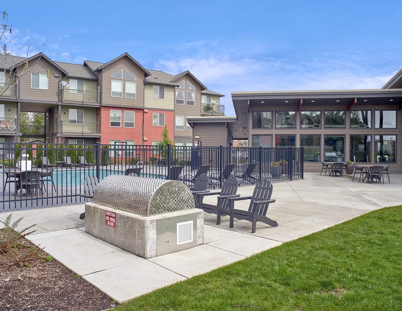 A pool area with lounge chairs, a barbecue grill, and a fenced patio.