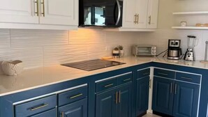 Une cuisine avec des meubles blancs, un plan de travail bleu et un four à micro-ondes.