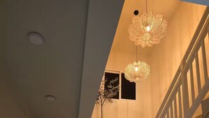 Un escalier avec une rampe blanche, une plante en pot et un luminaire au plafond.