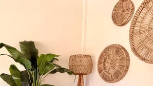 Un salon avec un canapé beige, une grande plante verte et un lampadaire à pied en fibres tressées.