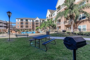 A pool area with lounge chairs, picnic tables, and a barbecue grill. - Landing | Amazing 2BD, Clubhouse (Corpus Christi)