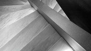 Una scala dal design moderno, con un rivestimento in marmo e superfici scure.
