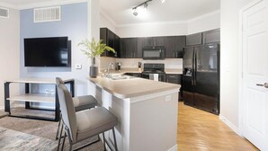Una cocina moderna con armarios oscuros, un refrigerador de acero inoxidable y una isla integrada con un lavamanos.
