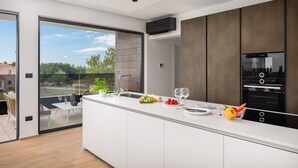Eine moderne Küche mit einer großen Kochinsel, einem Bosch-Backofen und Blick ins Freie.