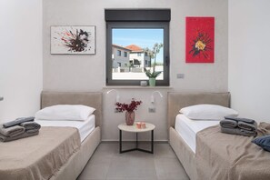 Una habitación con dos camas, una mesita con un florero y obras de arte en las paredes.