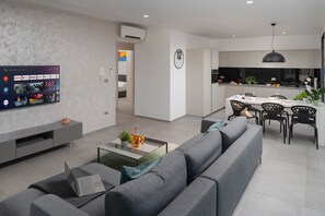 Un salón moderno con sofá, mesa de centro y televisor mostrando opciones de películas.