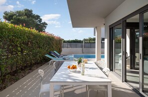 Un patio con mesa, sillas, piscina y seto.